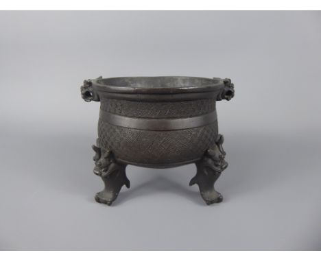 An Antique Chinese Bronze Censer, tripod base with incised motif decoration, mask handles with ball and claw feet.
