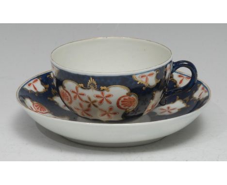 A Worcester Old Japan Star pattern teacup and saucer, typically decorated on a scale blue ground, picked out in gilt with lea