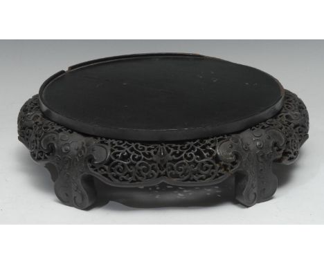 A large 19th century Chinese black lacquer and hardwood stand, circular plateau, the base carved in relief, shaped apron and 