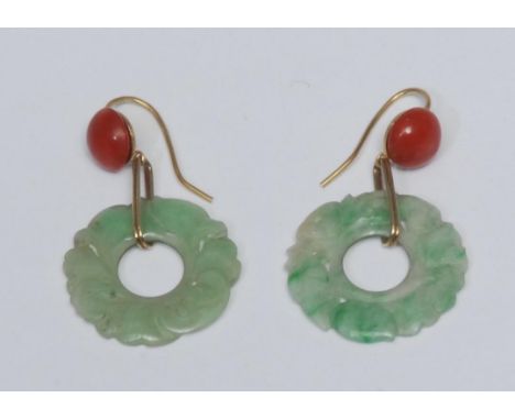 A pair of carved green stone and coral drop earrings, each with a carved floral green stone ring drop, possibly jade, suspend
