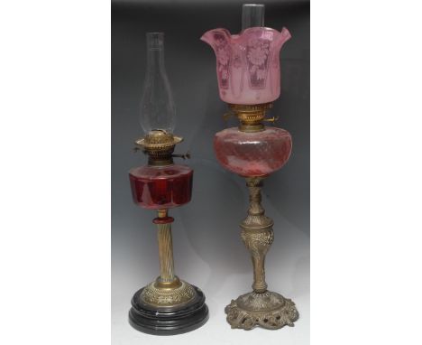 A Victorian Rococo style brass oil lamp, pink glass font, acid etched pink glass shade, 70cm over shade; another, cranberry g