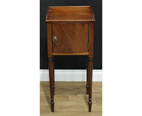 A George III mahogany bedroom cabinet, rectangular top with three-quarter gallery above a door, brass axe-head handles, turne