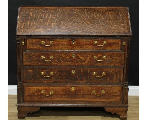 A George III oak bureau, crossbanded fall front enclosing a small door, small drawers and pigeonholes, above four long gradua