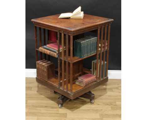 An Edwardian oak revolving bookcase, square top above an arrangement of book provisions, four slats to each side, metal-mount
