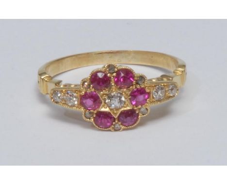 A diamond and ruby cluster ring, central oval mixed old cut diamond surrounded by a ring of six vibrant pinky red rubies, eac