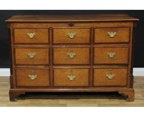 A George III oak chest, oversailing rectangular top above three rows of three mahogany banded short drawers, flanked by inset