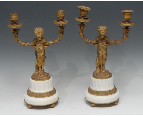 A pair of Neo Classical ormolu and white marble two-light candelabra, each cast as a scantily clad young satyr supporting bra