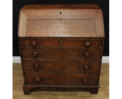 A George III oak bureau, fall front enclosing an arrangement of pigeonholes and small drawers, above four graduated cockbeade