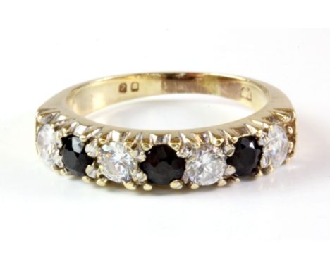 A yellow metal (tested 9ct gold) sapphire and white stone set half eternity ring, (K).