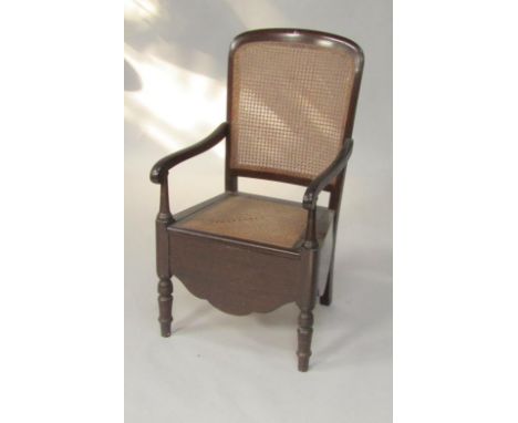 A Victorian mahogany commode chair, with a cane seat and back, ceramic pot, raised on turned legs.