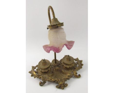 An early 20thC rococo design lamp and inkwell, the shaped outline with two ink pots of compressed circular form, centred by a