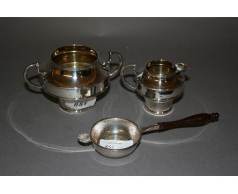 Small silver cream jug with matching sugar basin and a silver tea strainer