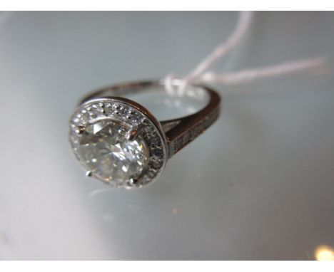 Platinum and diamond solitaire halo ring, the central round brilliant cut diamond weighing approximately 1.50ct surrounded by