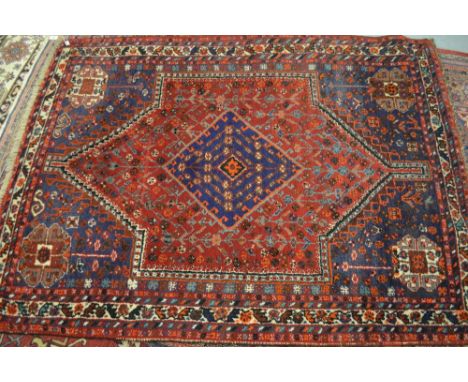 Shiraz rug with a medallion and all-over stylised floral design on a red ground with corner designs and borders