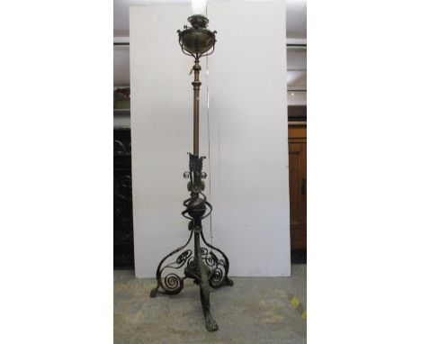 A Victorian wrought iron and brass standard lamp with a height adjustable column on a bulbous, leaf and scrolled tripod base,
