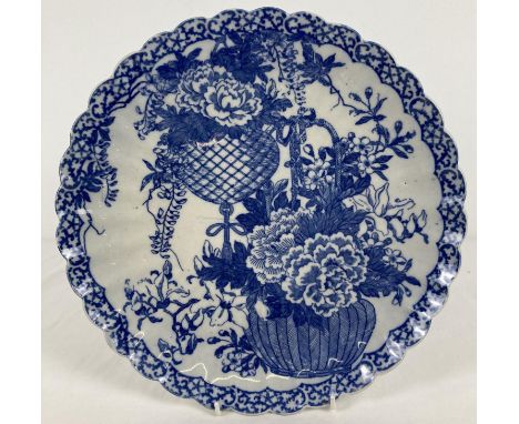 An Oriental blue &amp; white ceramic charger with scalloped rim and floral basket design. Decorated with feather and scroll p