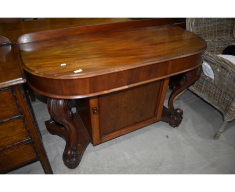 A Victorian mahogany console table having scroll legs, on castors, intergral cupboard, overall width approx. 122cm