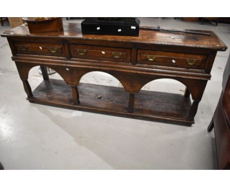 A period oak dresser base , possibly European having three frieze drawers and open shelf, with additional apron possibly bein