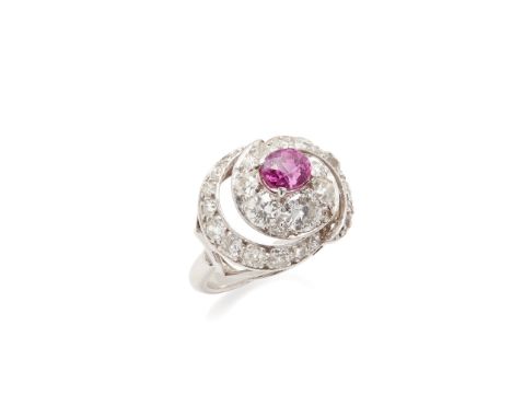 A pink sapphire and diamond set ring claw set with an oval-cut pink sapphire, in a scrolling surround set with old round-cut 