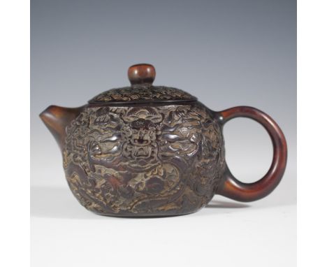 DESCRIPTION: Carved Chinese amber teapot. Features intricately carved designs of dragons enveloped by clouds and spiraling pa