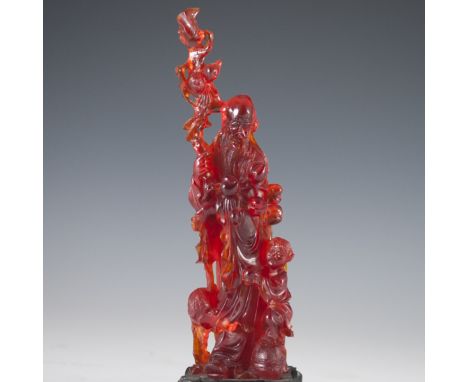 DESCRIPTION: Carved press amber figurine of the Chinese deity of longevity. Seen here holding a staff and holding strings of 