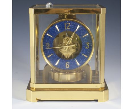 DESCRIPTION: Jaeger LeCoultre Atmos Clock featuring a sleek brass case with glass panels encasing the dial comprised of lapis