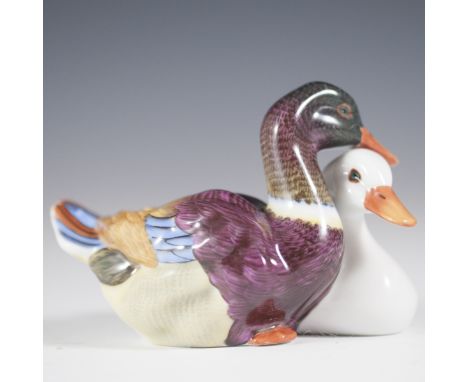 DESCRIPTION: Herend porcelain figurine of an all white duck nestling with a multi-hued duck with vibrant accents. Intricately