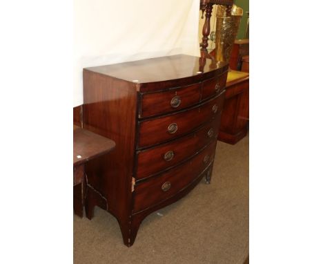 An early 19th century mahogany bow-front chest of drawers with brass handles bearing Prince of Wales feather motif and raised