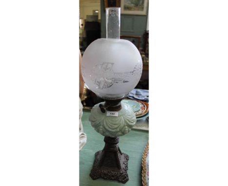 An iron base green glass oil lamp with etched globe