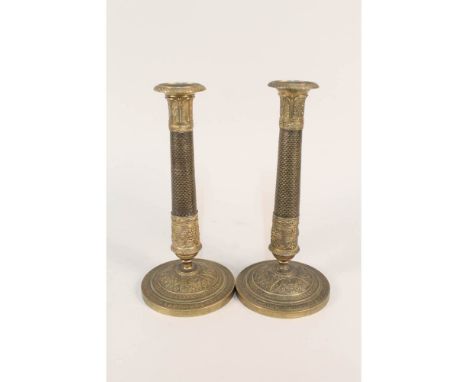 A pair of early 19th Century French gilt brass candlesticks with engine milled decoration to the cylindrical columns and wide