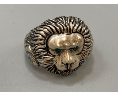 A silver ring with lion mask decoration set with emerald eyes, weight 9.33grams