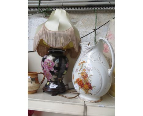 A table lamp with pink flowers on black ground, and a large jug 