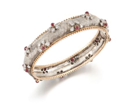 A two colour ruby and diamond bangle, the white centre with applied cabochon ruby and brilliant-cut diamond floral clusters, 