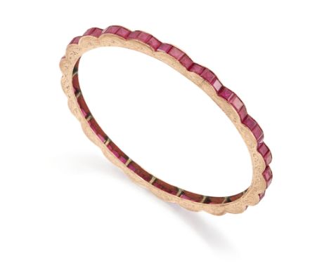 A synthetic ruby bangle,&nbsp;with a row of calibr&eacute; cut synthetic rubies, (one lacking), channel set to the scalloped 