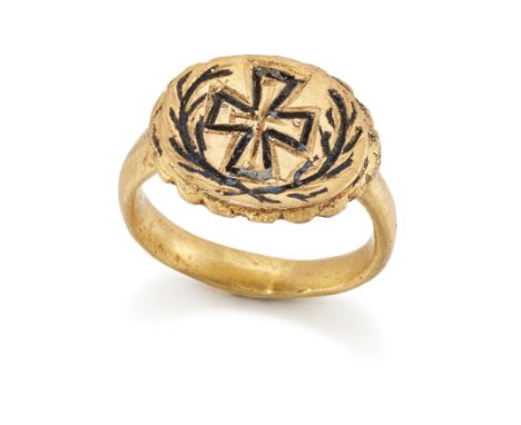 An antique gold ring, probably Byzantine, the oval bezel engraved with a niello cross above crossed palm leaves, to scalloped