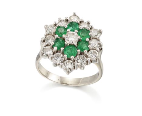 A diamond and emerald target cluster ring, a central brilliant-cut diamond, to two row mixed cut emerald and brilliant-cut di