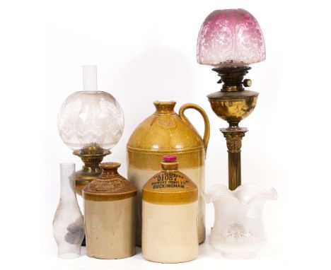 A BRASS OIL LAMP of Corinthian column form with cranberry glass tinted shade, 75cm high overall together with a further Victo