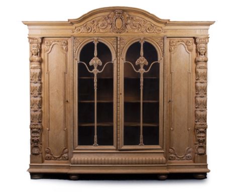 A LARGE CARVED LIGHT OAK CUPBOARD the central crest above two glazed doors, flanked by two panel door, carved figure head and