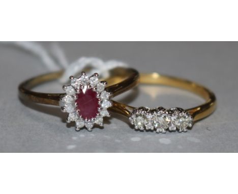 A ruby and diamond 9ct gold cluster ring and an 18ct gold and three-stone diamond ring.