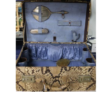 A 1930's python skin vanity case containing two silver mounted brushes, a mirror and a comb, case 51cm.