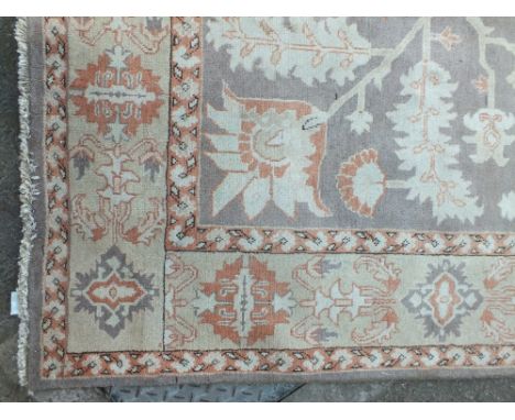 AN EASTERN WOOLLEN 20TH CENTURY RUG / CARPET, the floral central pattern on a mainly green ground with beige floral bands to 