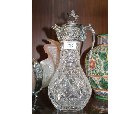 A SILVER PLATED CUT GLASS CLARET JUG WITH HERALDIC LION FINIAL 