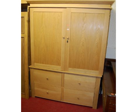 A contemporary light oak double door wardrobe, the recessed panelled upper doors enclosing central clothes rail, over base fi