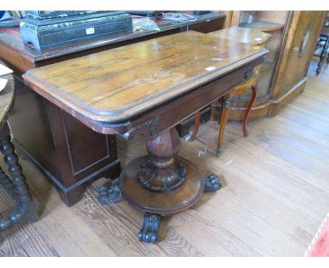 An early Victorian rosewood foldover card table, the rectangular top enclosing a circular playing surface, on an octagonal ba