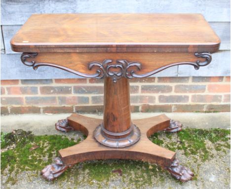 A Victorian rosewood fold-over card table with carved decoration, on turned column and quadraform lion paw supports, 36" wide