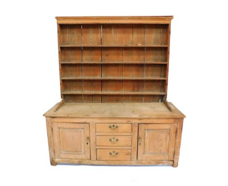 A Victorian pine dresser, with a four shelf plate rack, over three central drawers, flanked by two cupboard doors, raised on 