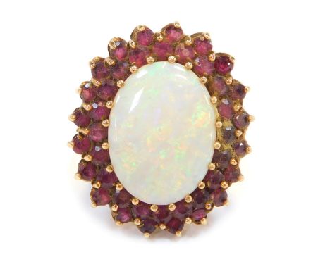 A cluster ring, with oval cut imitation opal surrounded by garnets, in a yellow metal setting, unmarked, believed to be 9ct g