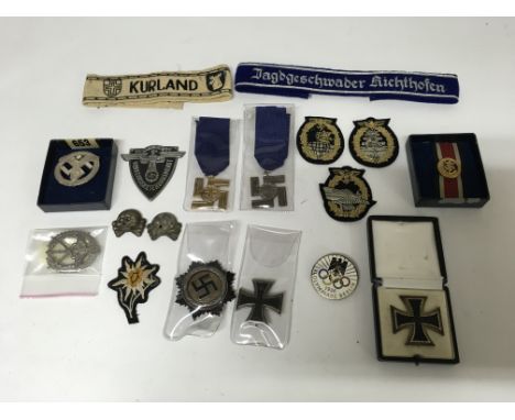 A group of German badges including an iron cross, SS flower patch and SS swastika medals.