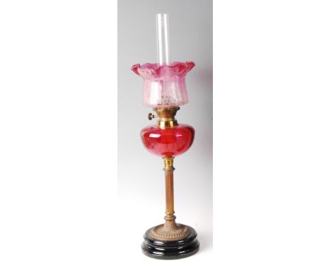 A late Victorian brass and cranberry glass pedestal oil lamp, with acid etched cranberry tinted shade and plain cranberry gla
