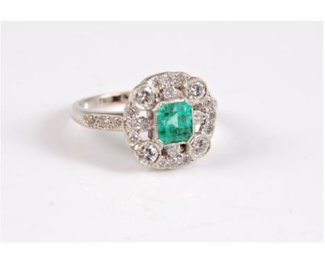 An early 20th century emerald and diamond ring, the central square emerald cut emerald, in rubover mount, surrounded by an ou